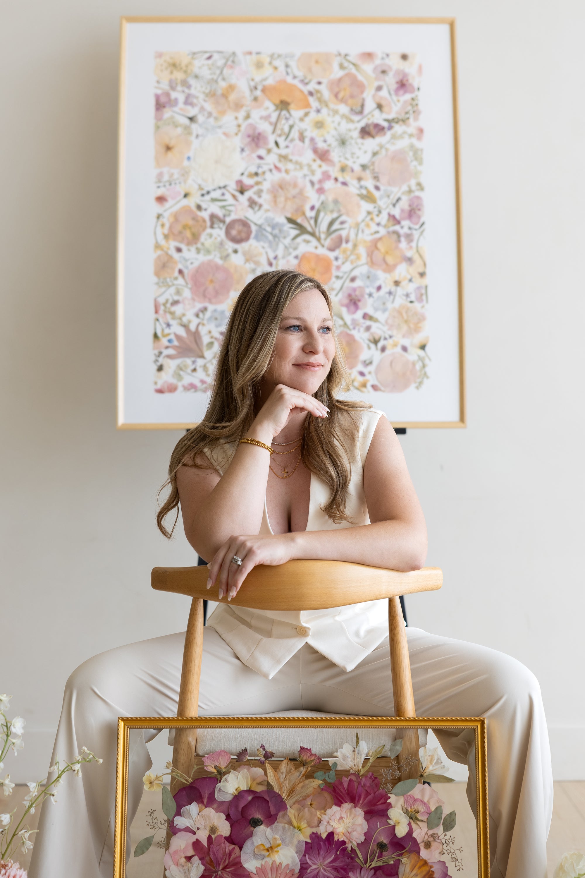 Mariah McDuffie, founder of Preserve My Petals, with a large pressed flower piece behind her