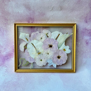 Pressed lavender and white flowers in a gold floating frame.