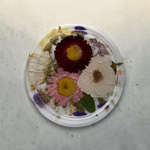 Round resin ring dish with preserved burgundy, pink and white flowers.