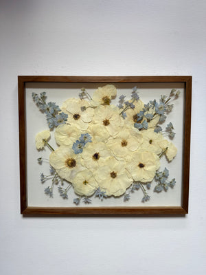 Pressed cream flowers in a round bouquet with soft gray greenery, in a dark wood floating frame.