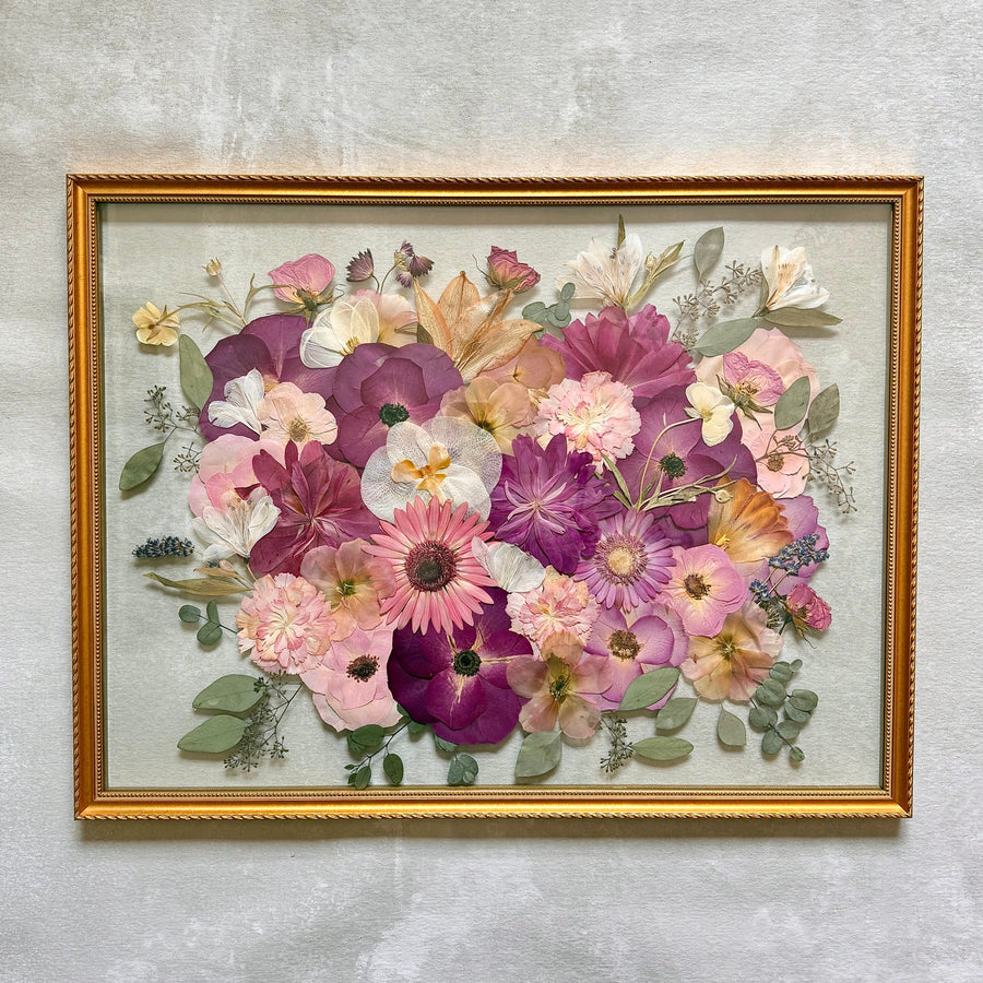 Pressed pink, magenta, peach and lavender flowers in a full bouquet design, in a gold floating frame.
