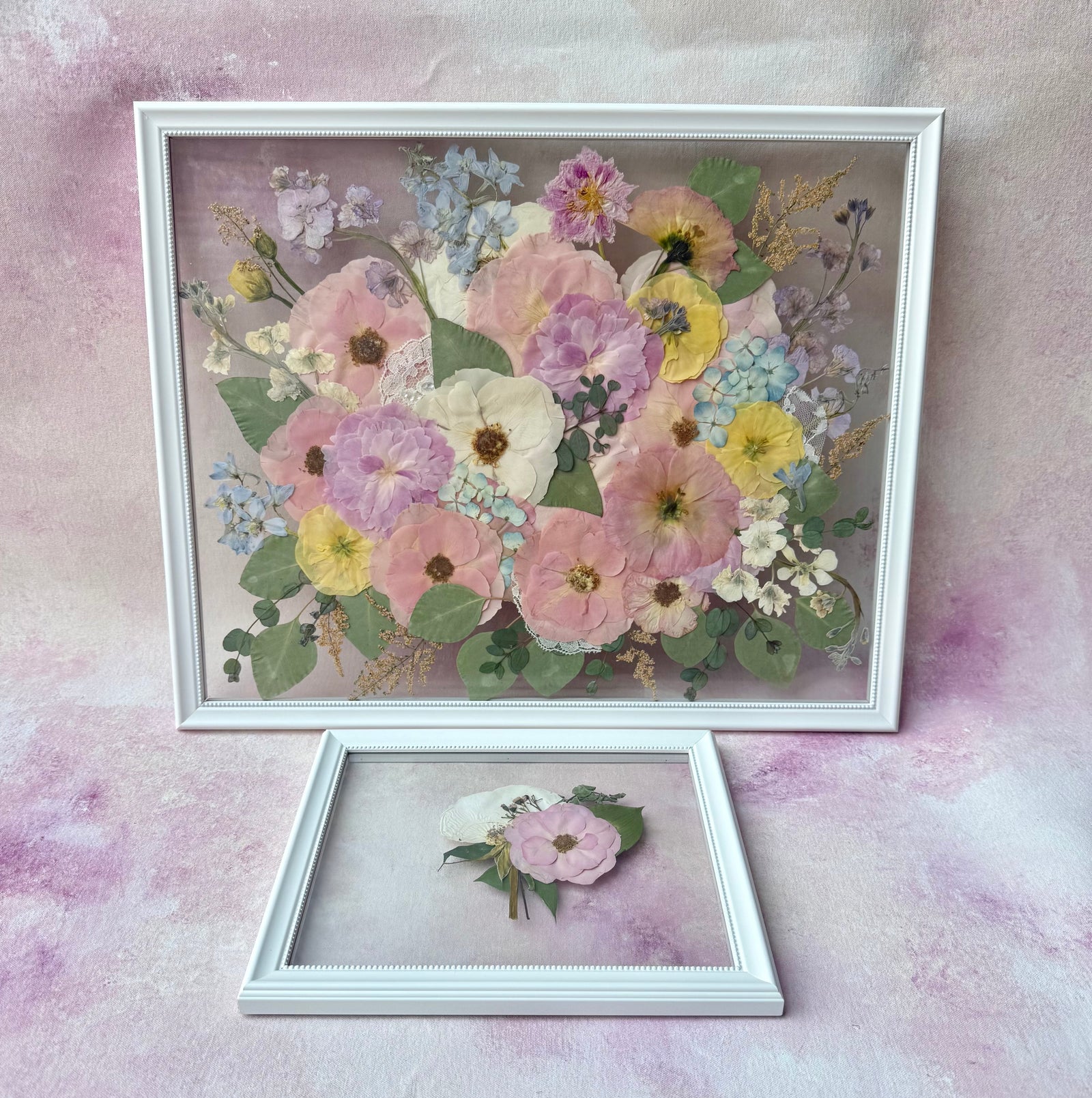 Pressed pink, peach and yellow flowers in a white floating frame, with a small frame holding one pink flower.