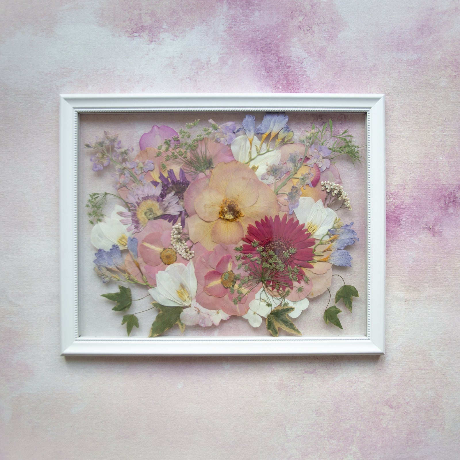 11x14 pressed flower frame with peach, pink and lavender flowers and greenery in a white floating frame.