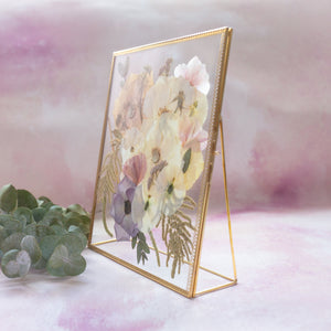 Side view of the gold freestanding frame with pressed flowers, showing its stand.
